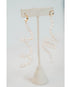flexible pearl drop earrings with gold huggie posts on a neutral earring stand against a light gray background