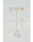flexible pearl drop earrings with gold huggie posts on a neutral earring stand against a light gray background