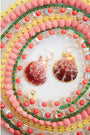 Shell-shaped earrings on a colorful beaded necklace with a white background