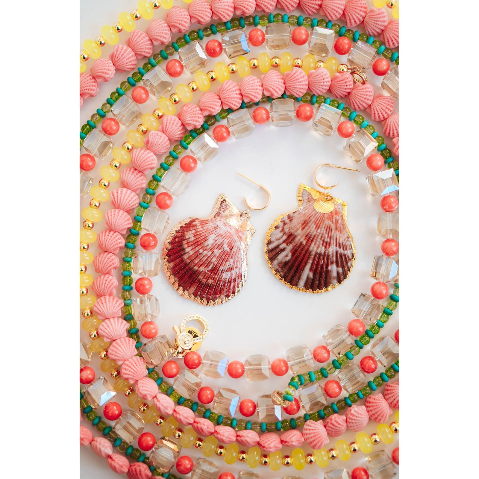 Shell-shaped earrings on a colorful beaded necklace with a white background