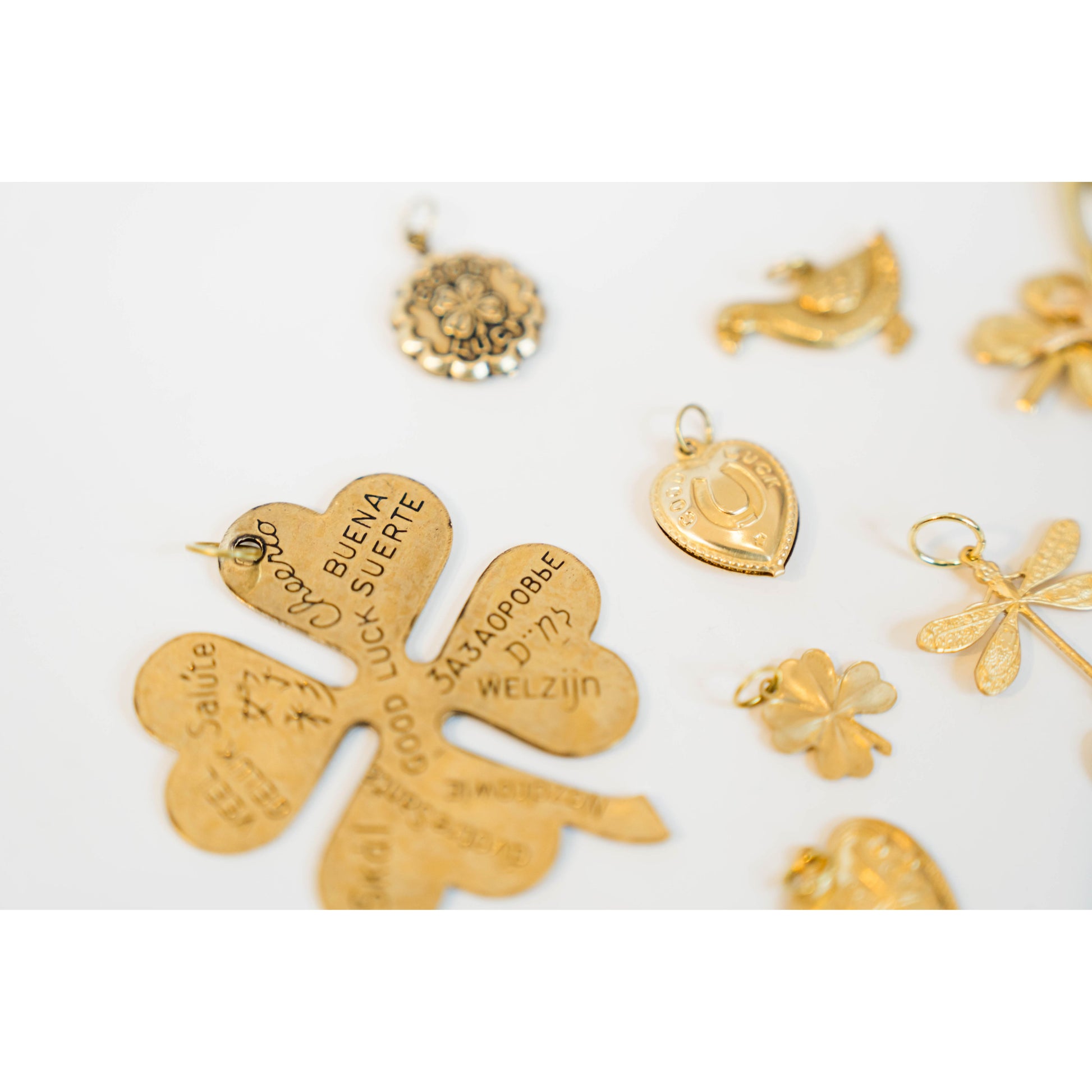 Collection of gold heart and clover charms on a white background