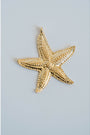 Gold detailed starfish pendant on a light gray background