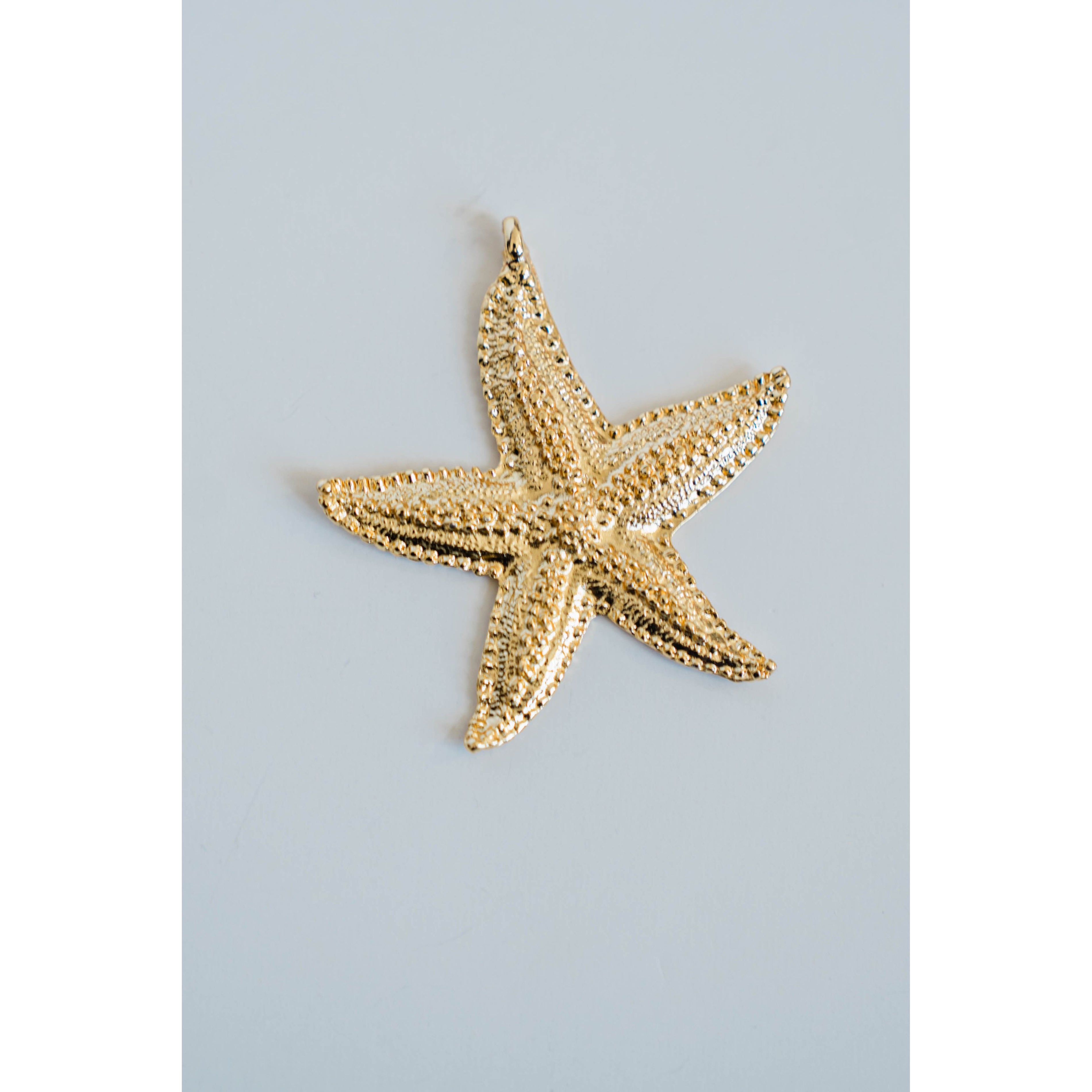 Gold detailed starfish pendant on a light gray background