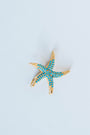 Starfish-shaped charm with turquoise stones on a light grey background