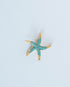 Starfish-shaped charm with turquoise stones on a light grey background