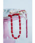 red beaded necklace with white pearl heart charms draped over a pretty cake stand