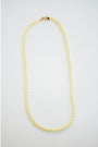 Gold and yellow beaded necklace on a light gray background