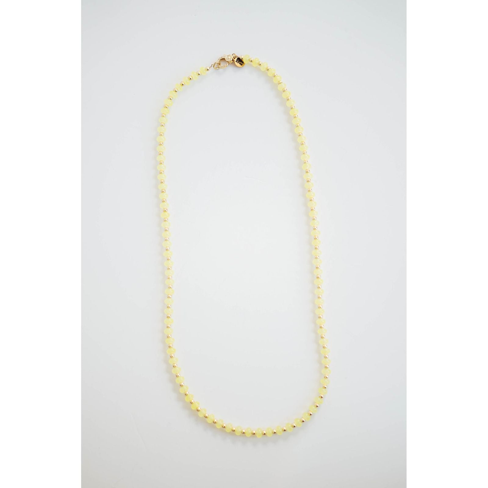 Gold and yellow beaded necklace on a light gray background