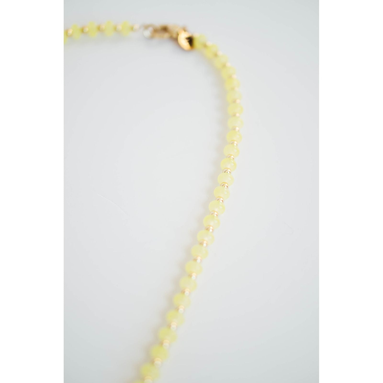 Necklace with yellow and gold beads on a light gray background