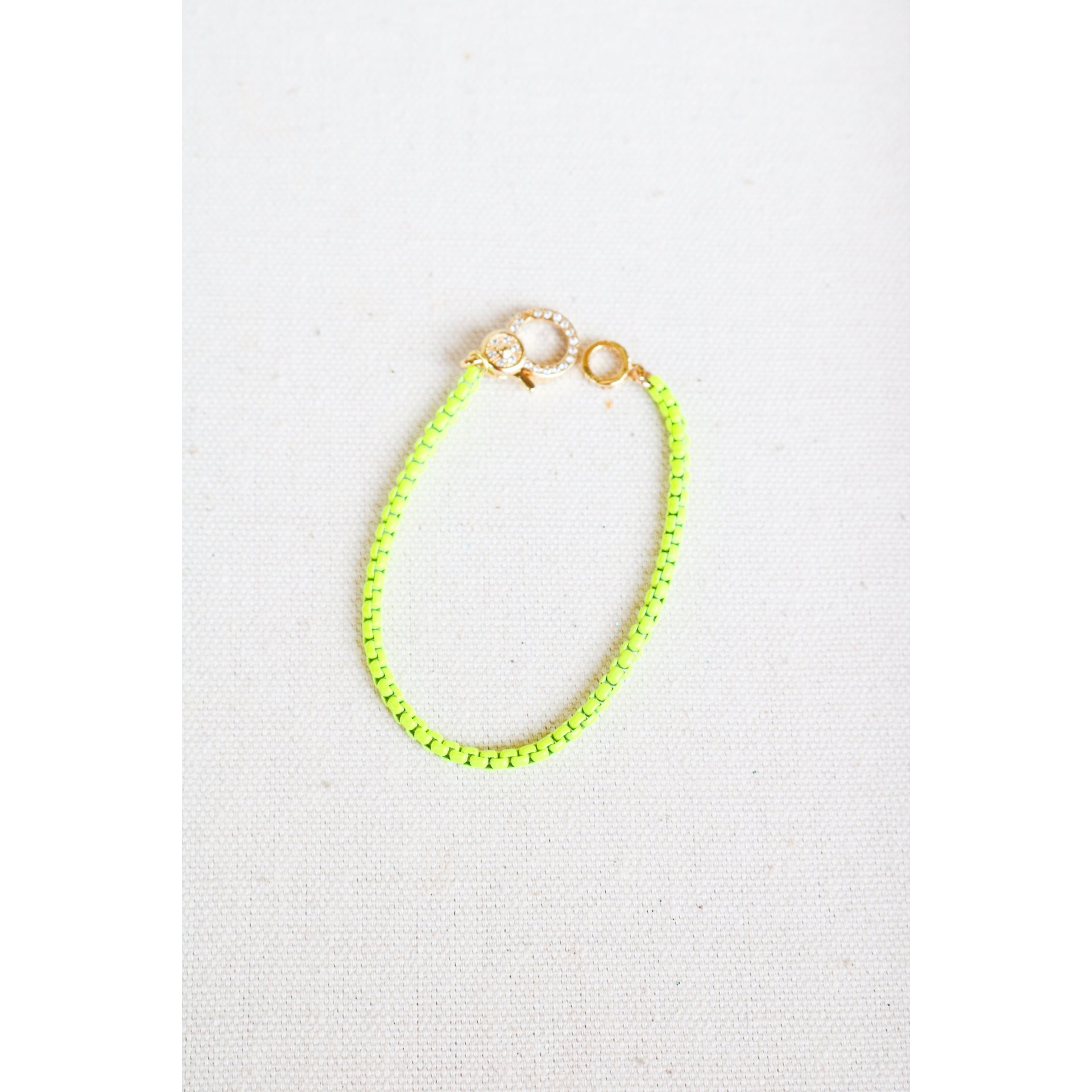 neon yellow enamel box chain bracelet with a gold pave lever clasp on a light grey background